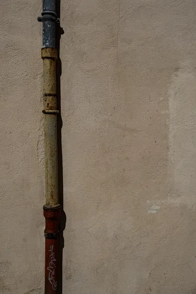 Verwittertes Fallrohr an einer Putzwand