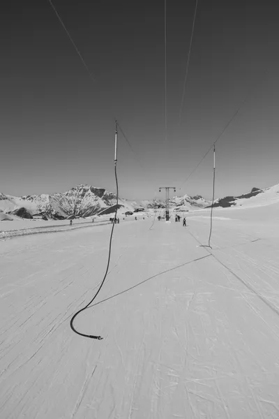 Ski lift with people on the slope in black and white
