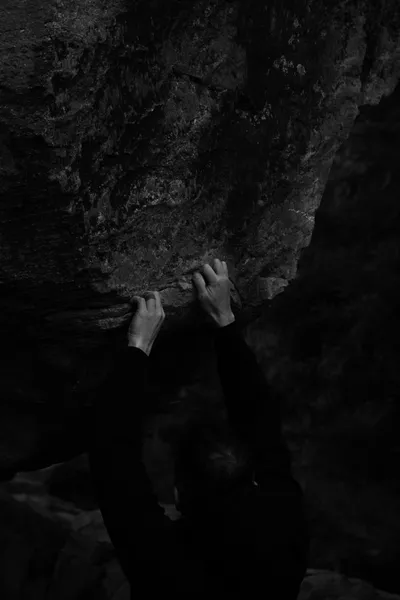 Hands gripping a rock face in black and white