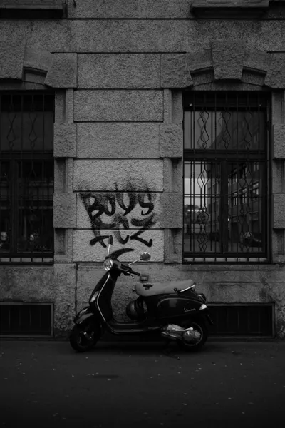 Vespa in front of a building facade with graffiti in black and white